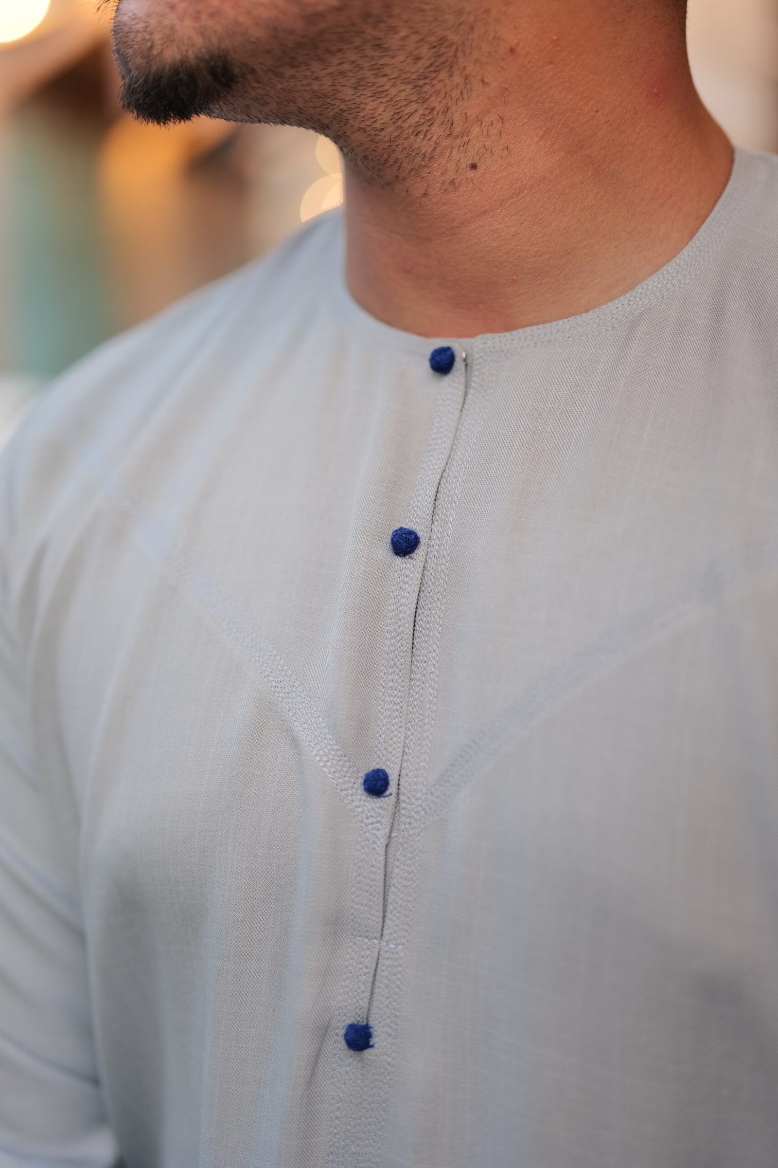 Grey thobe with blue button close up